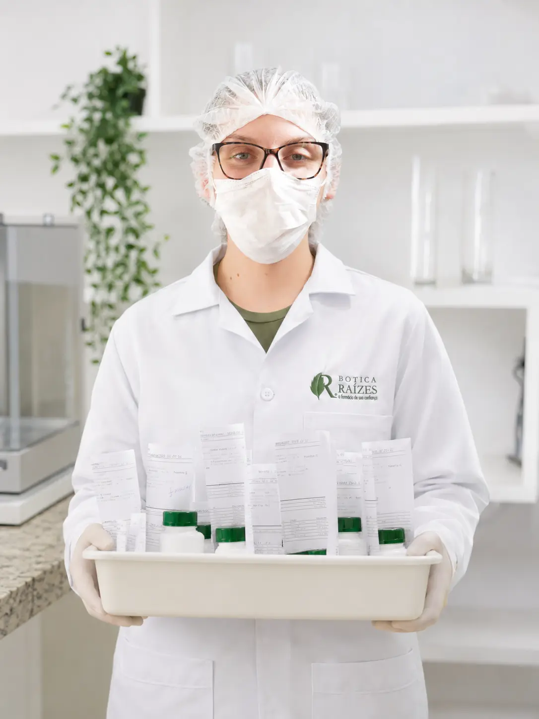 Farmacêutica da Botica Raízes segurando bandeja com fórmulas manipuladas